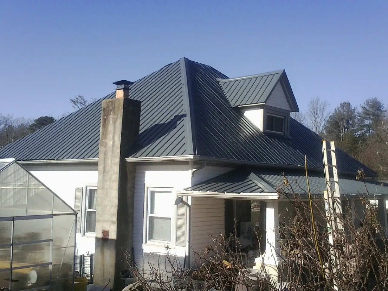 Dark blue standing seam metal roof on a white farmhouse with dormer — Slate & Tile Roof Repair by Roofing Brothers in Gypsum