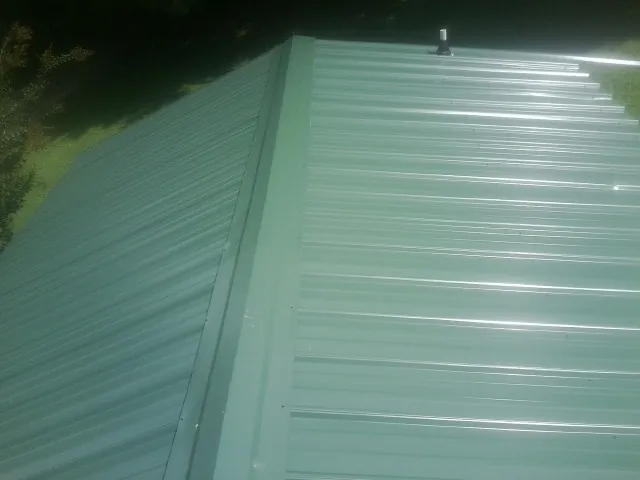 New green metal panels meeting at the ridge of a roof — Flat Roof Repair work by our crew in Gypsum