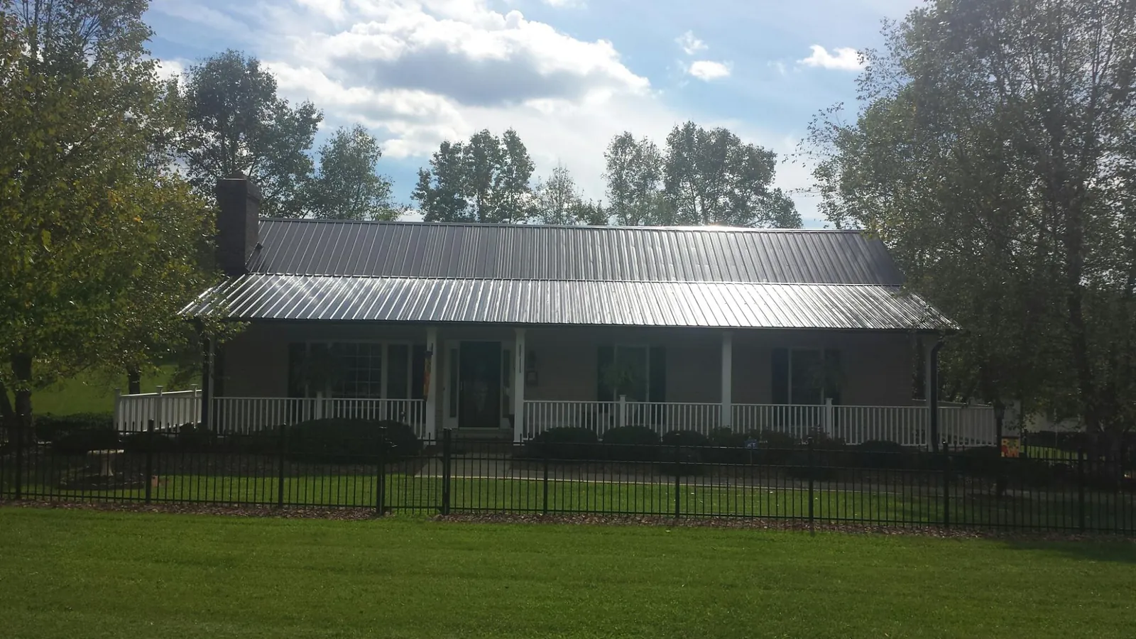 Gray metal roof on a brick ranch with a full width front porch — Gutter Guard Installation work by our crew in Gypsum