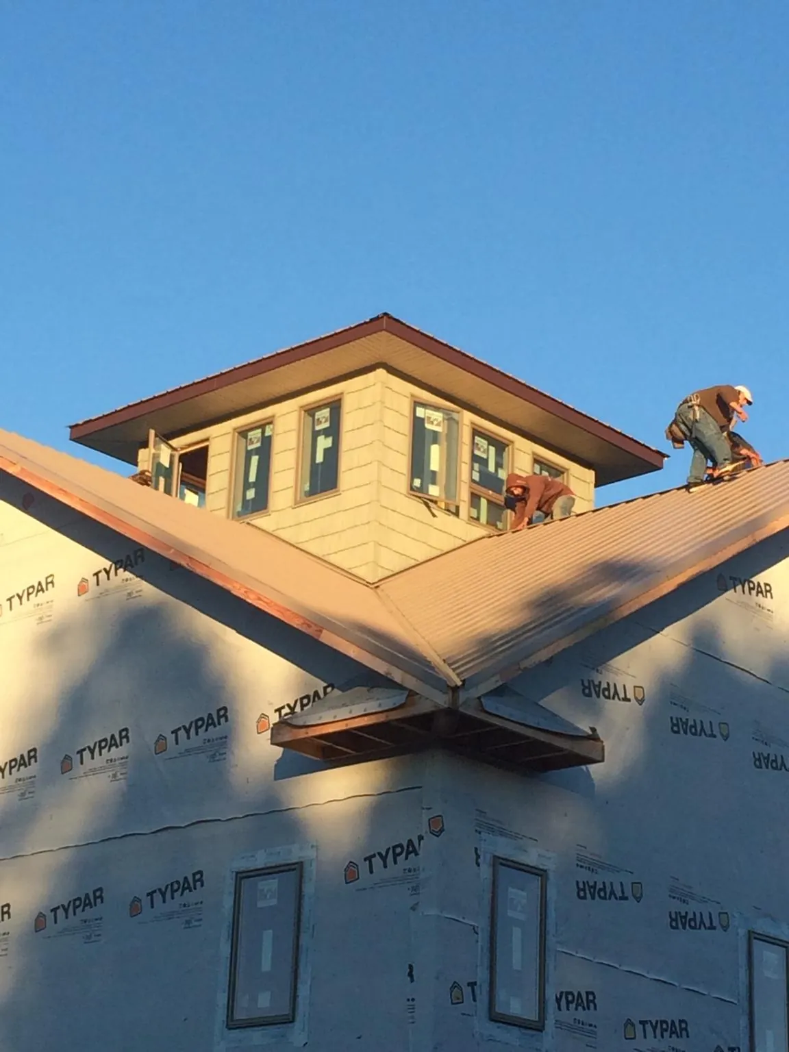 Roofers working around a rooftop cupola on a new metal roof at sunset — Roof Waterproofing in Gypsum by Roofing Brothers